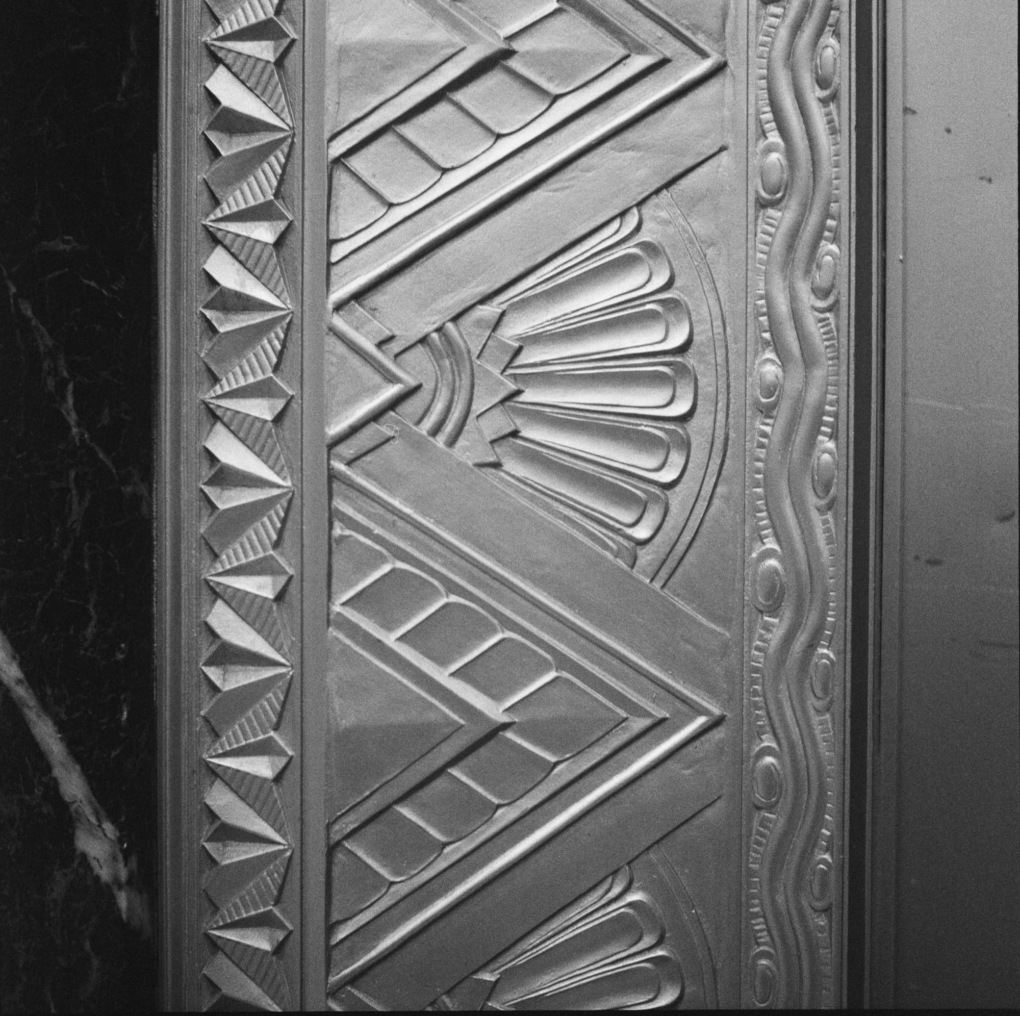 Close-up of Art Deco cast-metal sunburst and chevron ornament at 116 John Street