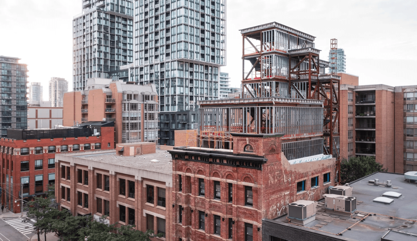 Steel-frame four-storey addition rising above the brick heritage building during restoration