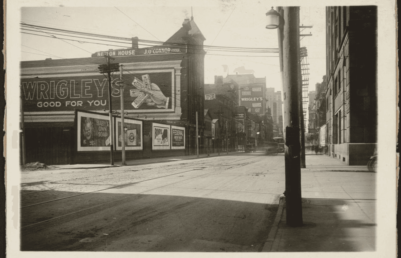 Archival photograph of King Street East with Nealon House and a Wrigley's billboard on the east wall