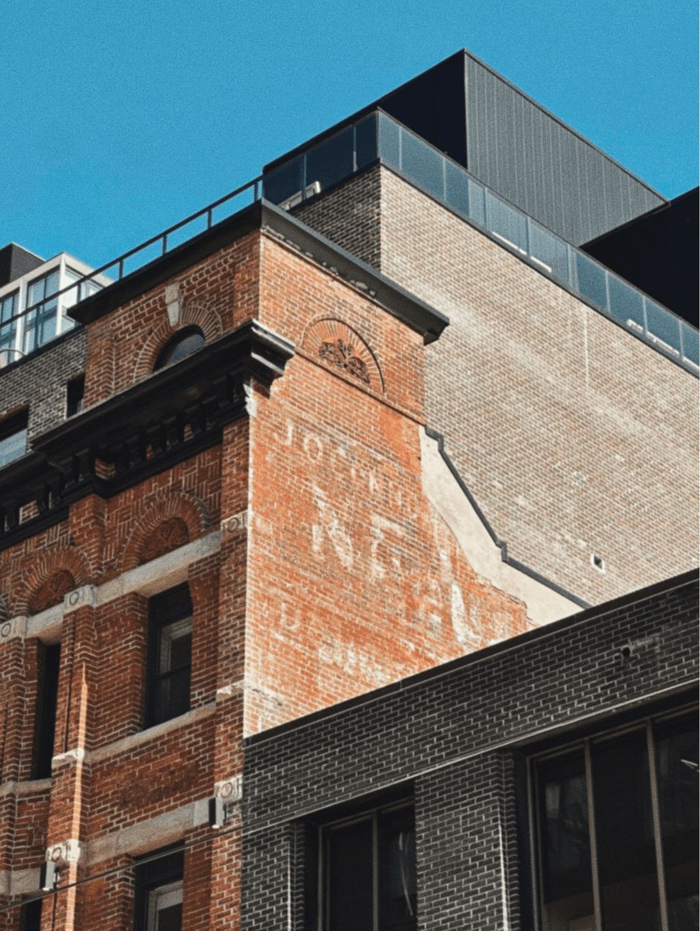 Ghost sign on the brick west wall reading Nealon House, J. O'Connor Prop., with the modern addition above
