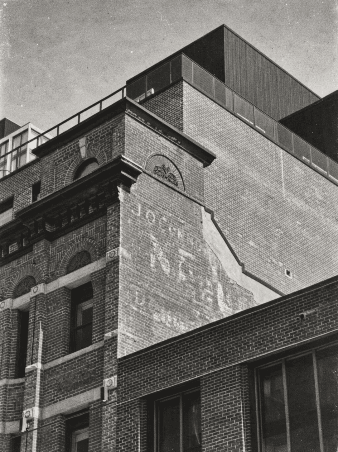 Brick corner of Nester Finn St. Lawrence Market in Toronto with a faded historic ghost sign and a modern rooftop addition
